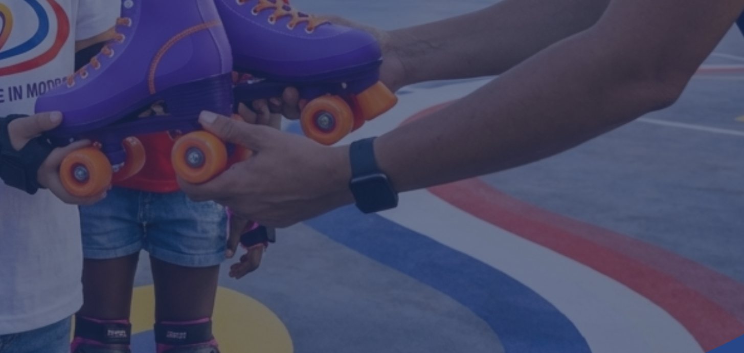 A coach handing roller skates to a young skater